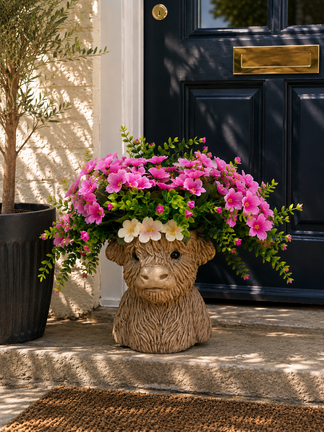 Highland Cow resin planter with pink floral arrangement on a doorstep