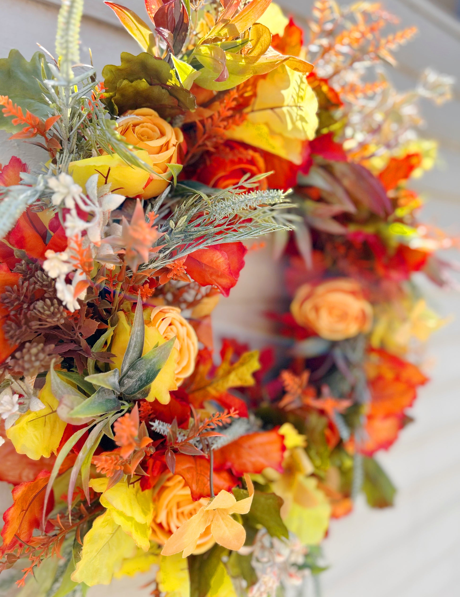 Close up detail of The Ember wreath showing scarlet leaves and golden yellow blooms