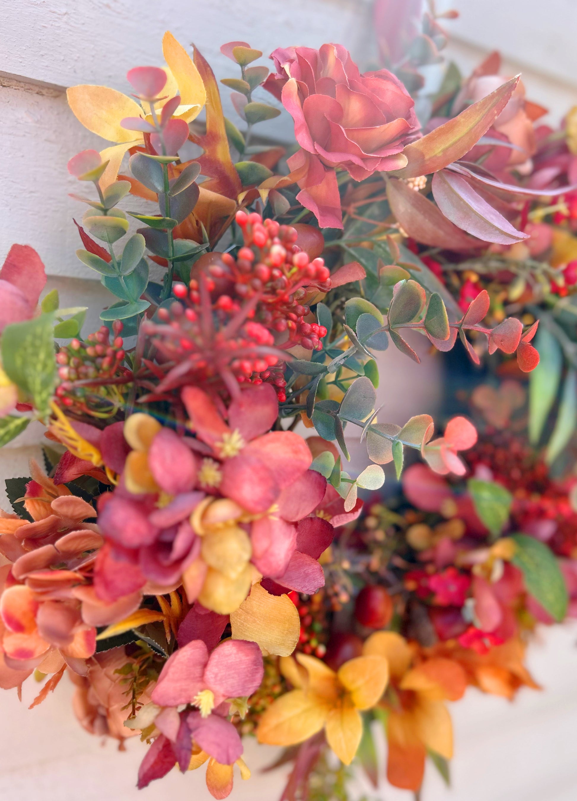 The Orchard autumn wreath full view on a white wall showing terracotta and coral tones