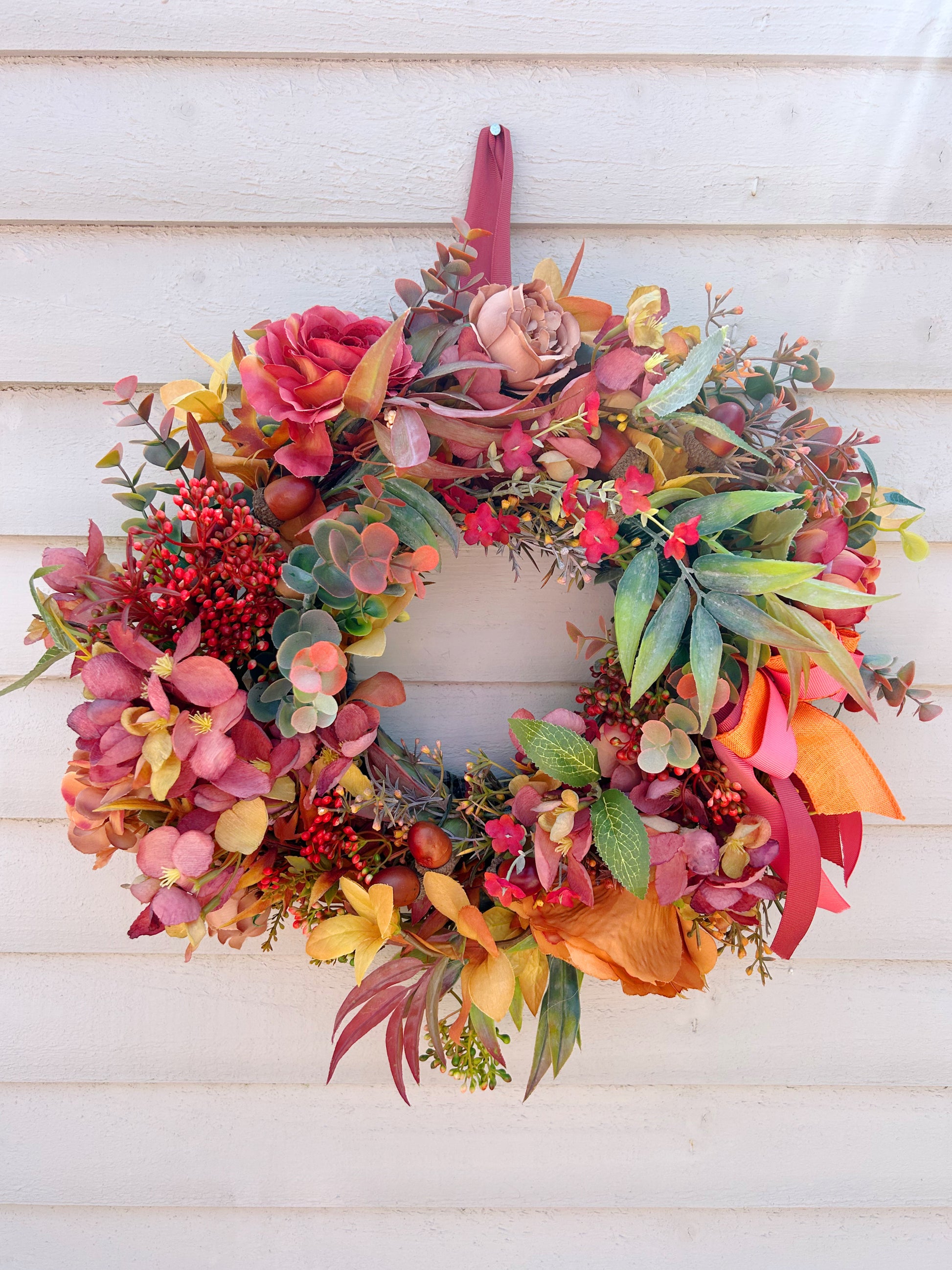 Close up of The Orchard wreath showing coral hydrangeas, red berries and eucalyptus detail