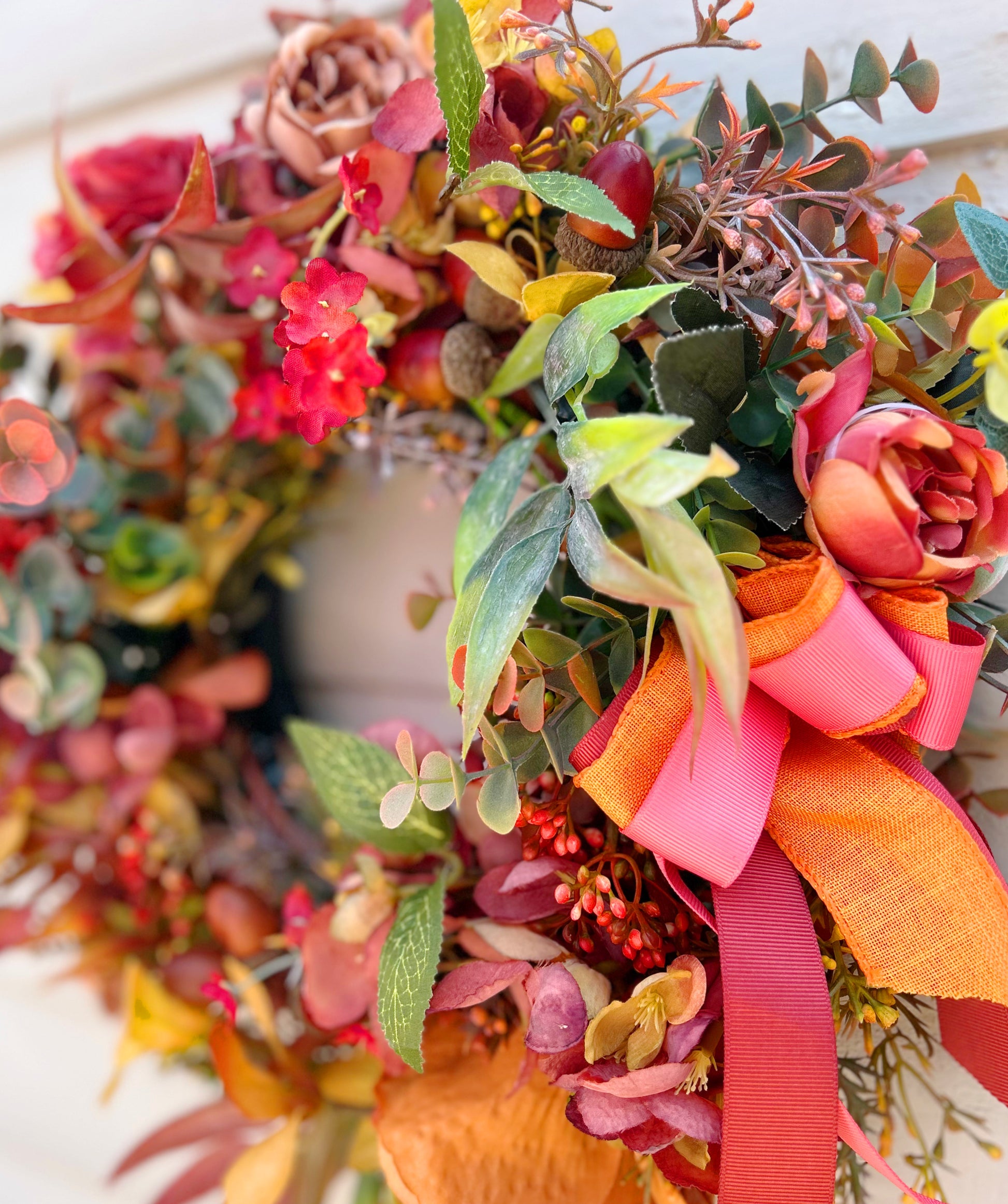 Close up of The Orchard wreath showing layered orange and coral ribbon bow detail