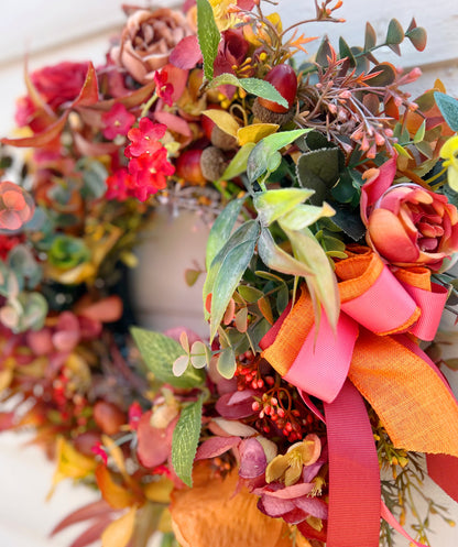 Close up of The Orchard wreath showing layered orange and coral ribbon bow detail